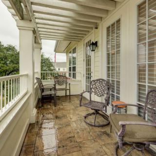 A cozy covered balcony with outdoor seating and elegant railings.