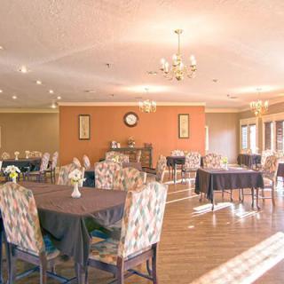 A spacious and elegantly decorated dining room with neatly arranged tables and chairs, featuring a warm ambiance and classic interior design elements.