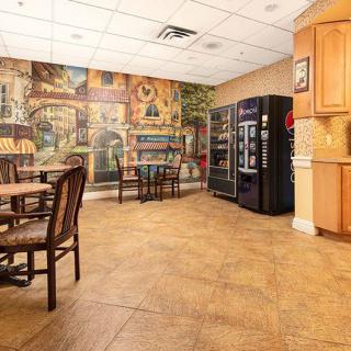 A cozy cafeteria with tables and chairs, vending machines, and a decorative mural on the wall.