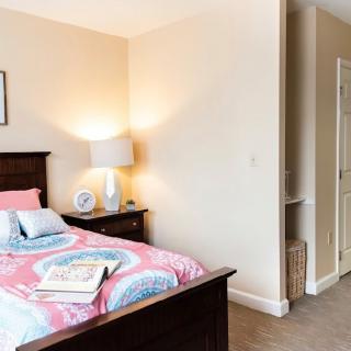 A cozy bedroom with a neatly made bed and a bedside lamp.