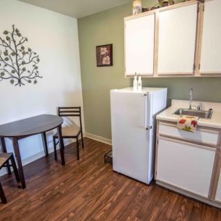A cozy kitchen area with a small dining table, chairs, a refrigerator, and a sink.