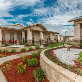 A scenic view of houses with beautifully landscaped gardens and pathways under a cloudy sky.
