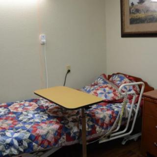 A hospital room with a single bed and overbed table.