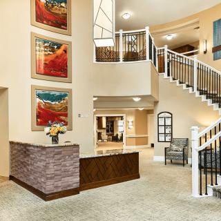 A well-lit lobby featuring a reception desk, staircase, and colorful artwork on the walls.