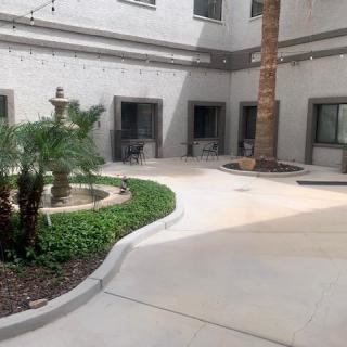 A peaceful courtyard featuring a fountain, palm tree, and outdoor seating areas.