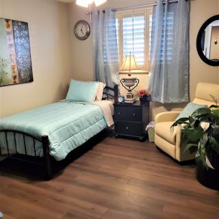 A cozy bedroom with a single bed, armchair, and light blue decor.