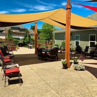 A sunny patio with shade sails, seating area, and outdoor furniture.