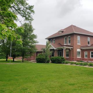 A charming brick house surrounded by lush greenery and a well-maintained lawn.