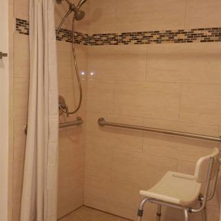 An accessible bathroom with a shower seat and grab bars.