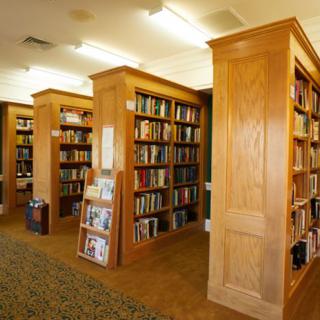 A quiet library room with wooden bookshelves filled with books.