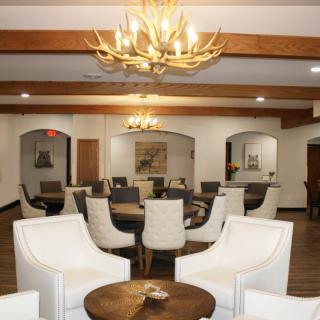 A spacious lounge with modern seating, wooden beams, and elegant chandeliers.
