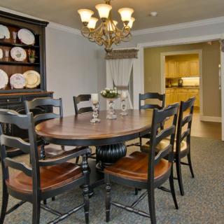 A cozy dining room featuring a round wooden table with matching chairs and an elegant chandelier overhead.