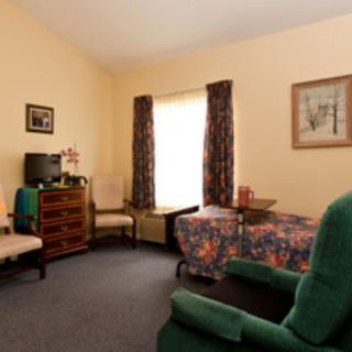 A cozy living room with comfortable chairs, a television, and floral decor.