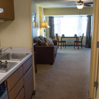 A cozy apartment with a small kitchenette leading into a living room area featuring a sofa and dining table.