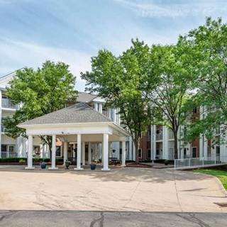 A spacious building entrance surrounded by trees with a wide driveway.