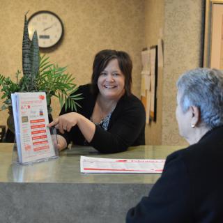 A receptionist interacting with a visitor at the front desk.
