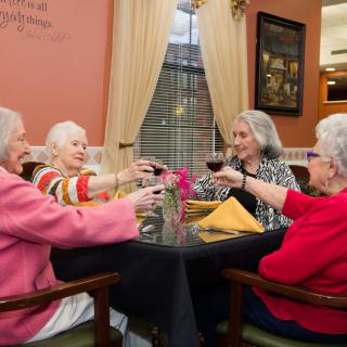 A group of senior women enjoying a toast together at a dining table.
