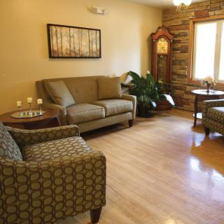 A cozy living room with comfortable seating, a grandfather clock, and decorative elements.