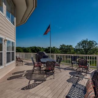 A scenic outdoor deck with patio furniture and an American flag under a clear blue sky.