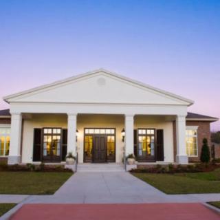 A classical-style building with columns at the entrance, viewed during the evening.