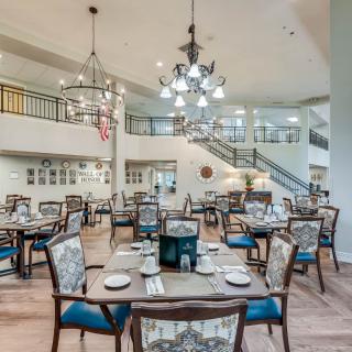 An elegant dining area with beautifully arranged tables and chairs, illuminated by chandeliers.
