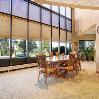 A spacious dining area with a wooden table and chairs, illuminated by natural light from large windows.