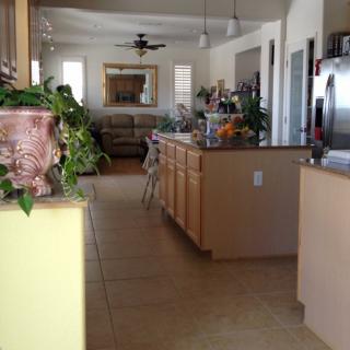 A modern kitchen with a central island, decorated with plants and featuring various appliances.