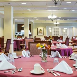 A sophisticated dining area with neatly arranged tables and chairs, featuring elegant place settings and floral centerpieces.