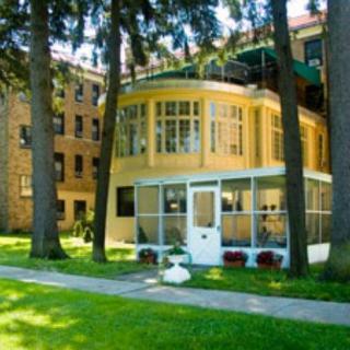 A sunny view of a building with large windows surrounded by trees and a well-kept lawn.