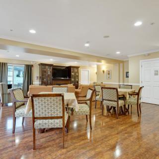 A spacious indoor dining area with tables and chairs on a wooden floor.