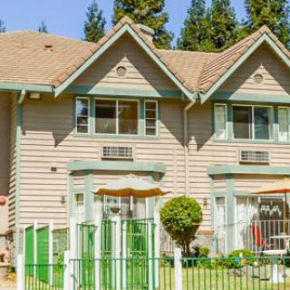 A suburban duplex with green accents and a manicured lawn.