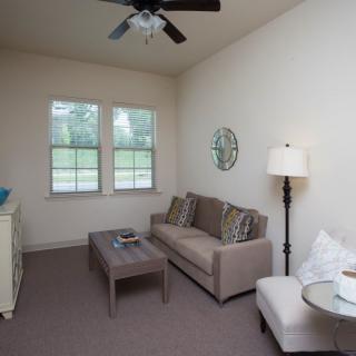 A cozy living room with a neutral color palette, featuring a sofa, coffee table, and tall lamp.
