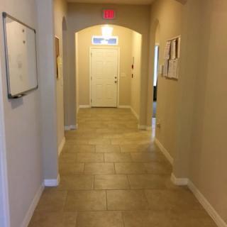 A well-lit hallway with tiled flooring leading to a door at the end.