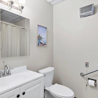 A modern bathroom with a sink, toilet, mirror, and wall art.