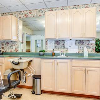 A spacious salon area featuring a hair washing station with cabinets and mirrors.
