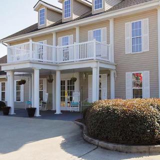 A large residential house with a prominent balcony and landscaped entrance.