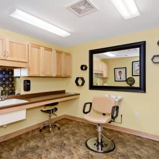 A well-lit hair salon station with a chair, large mirror, and wooden cabinets.