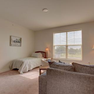 A cozy bedroom with a single bed, large window, and comfortable seating.