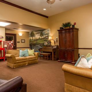 A cozy living room with comfortable sofas, a wooden cabinet, and warm lighting.