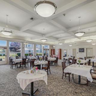 An elegant dining room with neatly arranged tables and large windows allowing natural light.