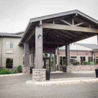 A modern hotel entrance with stone pillars and a covered driveway.
