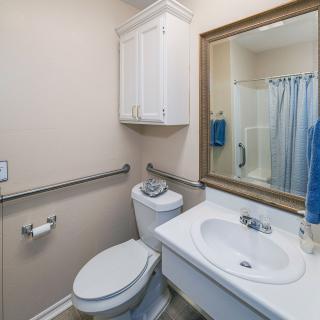 A small bathroom with a toilet, sink, mirror, and shower area.