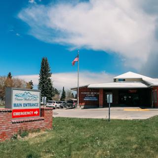 A medical facility under a clear sky with a flag waving in front.