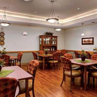 A cozy dining room with neatly arranged tables and chairs, complemented by warm lighting and decorative plants.