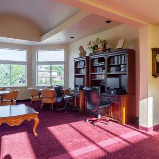 A spacious office with large windows, featuring a desk, bookshelves, and comfortable seating.