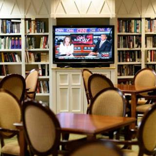 A cozy library setting featuring comfortable seating and a television displaying a program.