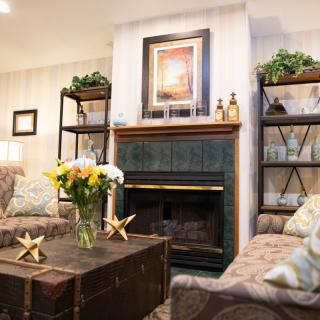 A cozy living room with a fireplace, bookshelves, and floral decor.