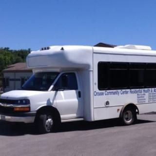 A white community transport bus is parked on a road.