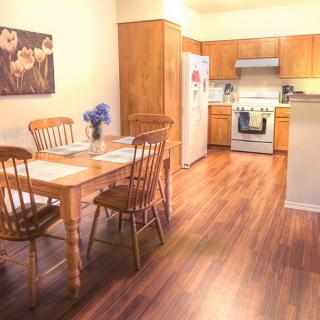 A cozy kitchen with a dining area featuring wooden floors and furniture, complete with modern appliances.