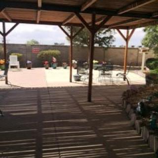 A shaded patio with seating overlooking a garden area.